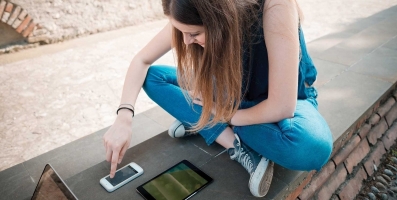 Visitor Stitching und Visitor Linking im Vergleich – junge Frau mit Smartphone und Tablet