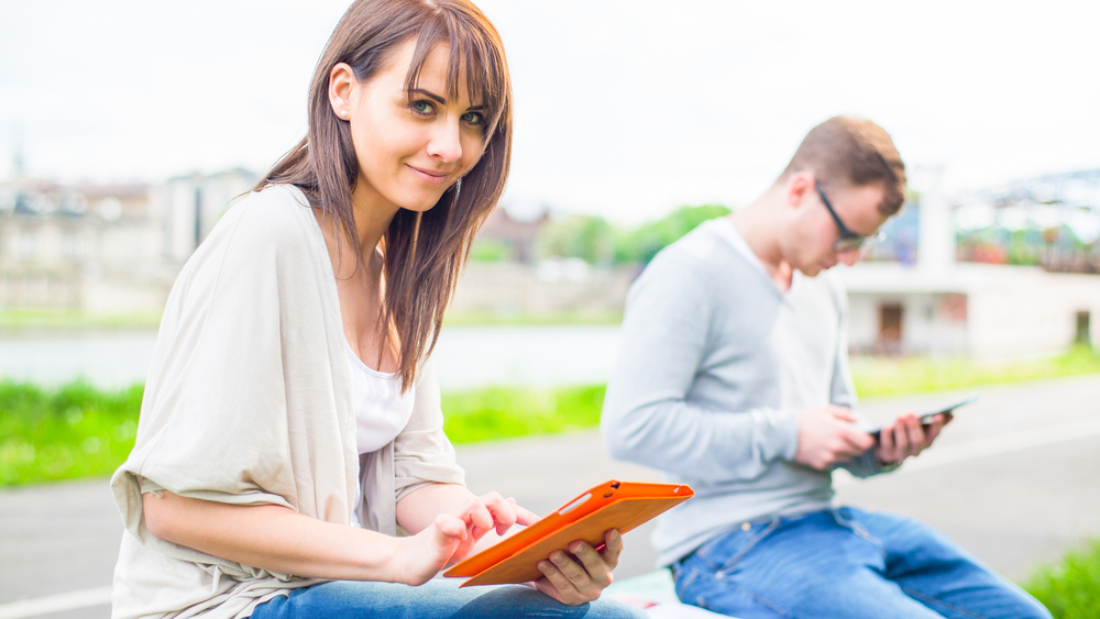 Woman reading tablet device Woman sitting outside reading tablet device