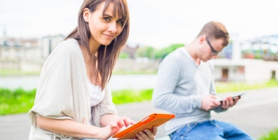 Woman sitting outside reading tablet device