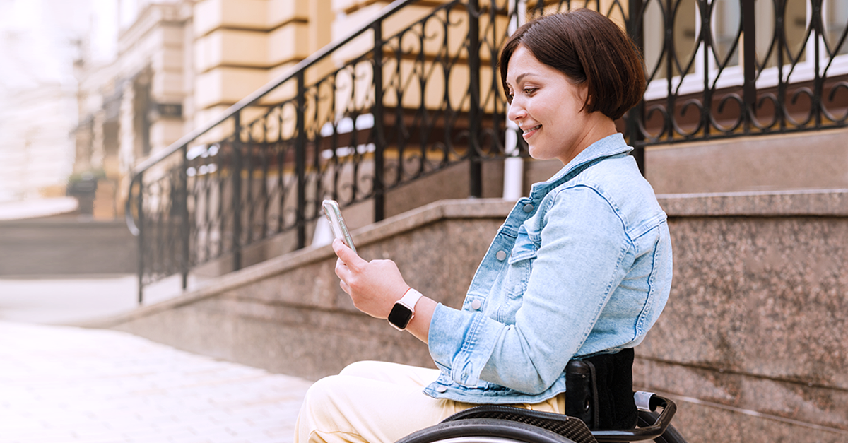 person in wheelchair looking at their mobile phone utilizing mobile features for cdps