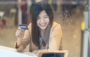 Smiling Asian woman on computer shows importance of considering both AI and data privacy